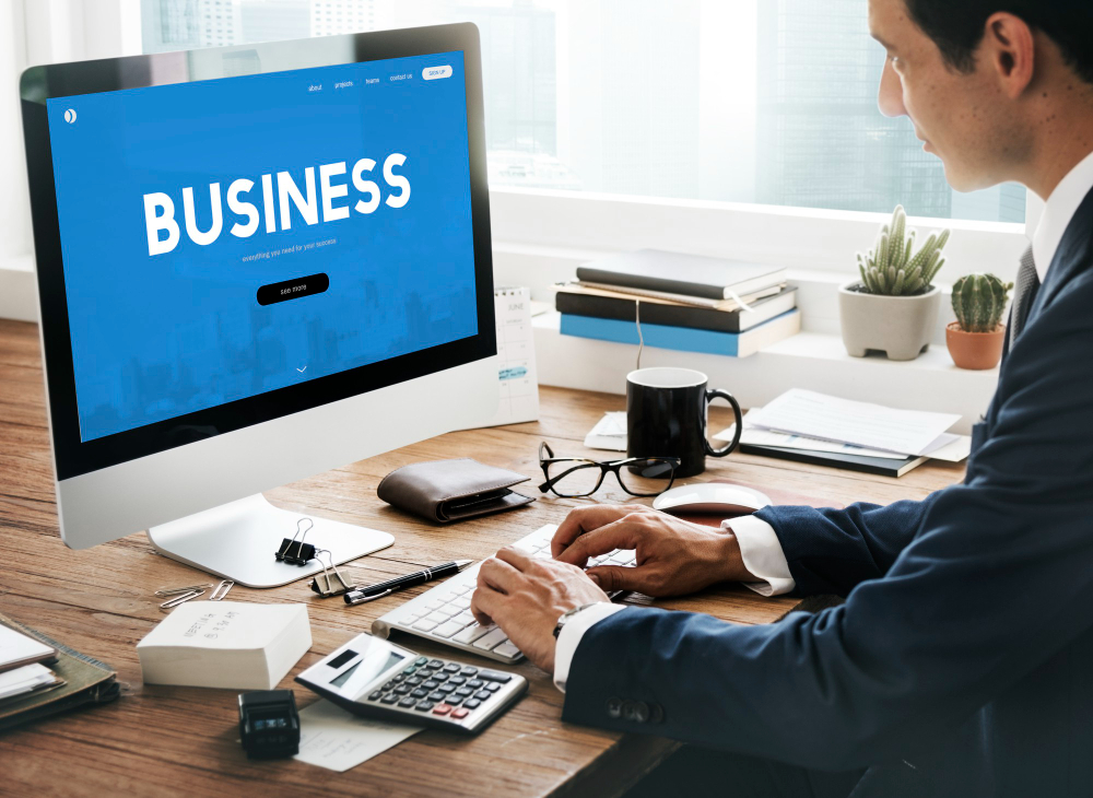 Businessman working on a computer displaying a business website template on a wooden desk in Newark, NJ.