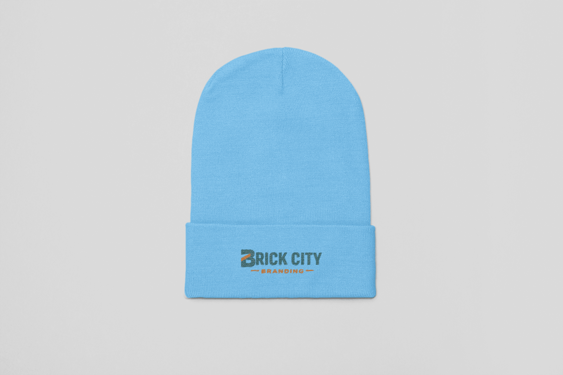 A light blue knit cuffed beanie featuring the Brick City Branding logo embroidered on the front cuff, centered against a neutral grey background.