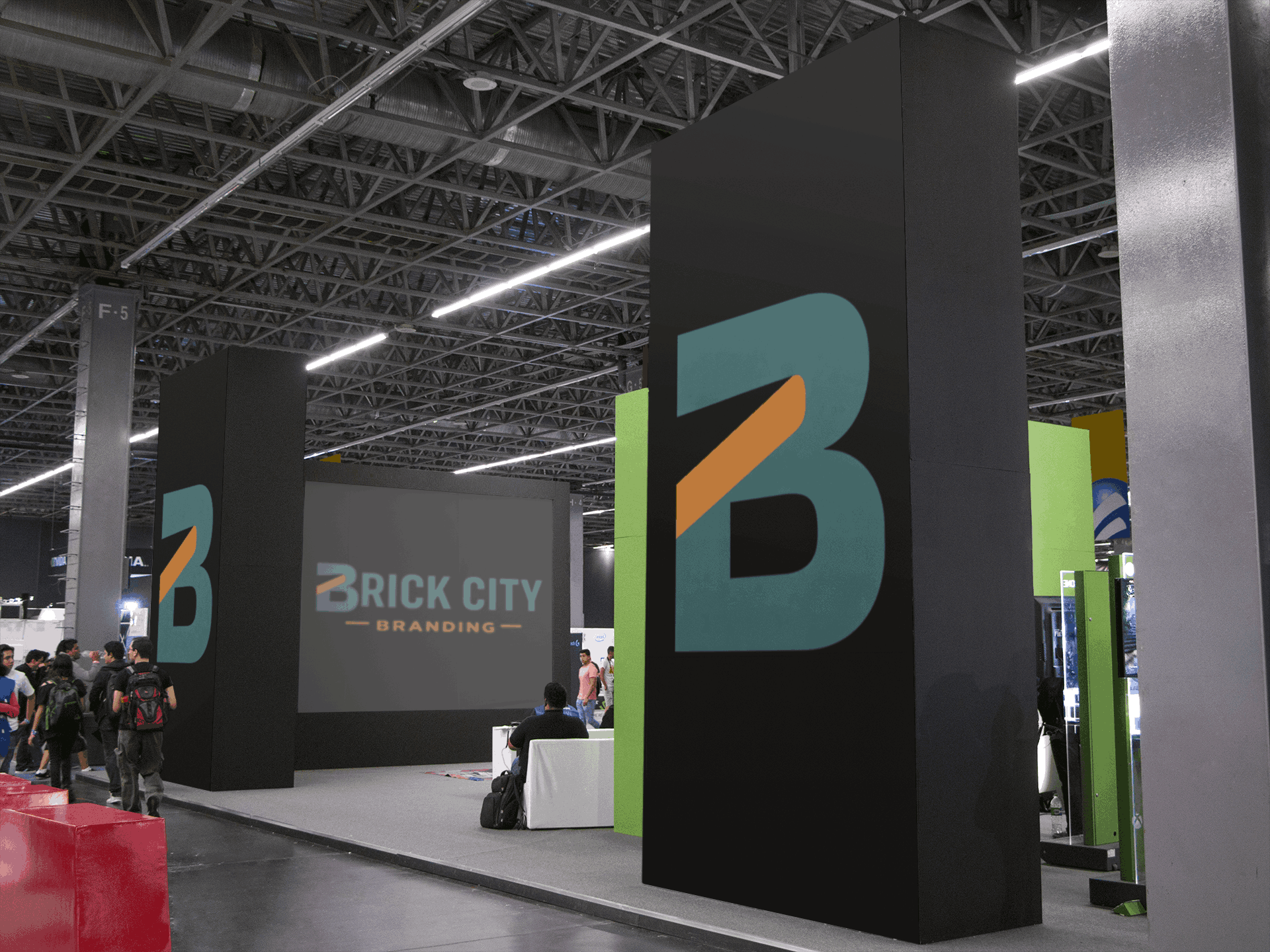 A large modern trade show exhibit and event branding for Brick City Branding featuring tall black monolith pillars with teal and orange logos and a large digital screen displaying the full brand name.