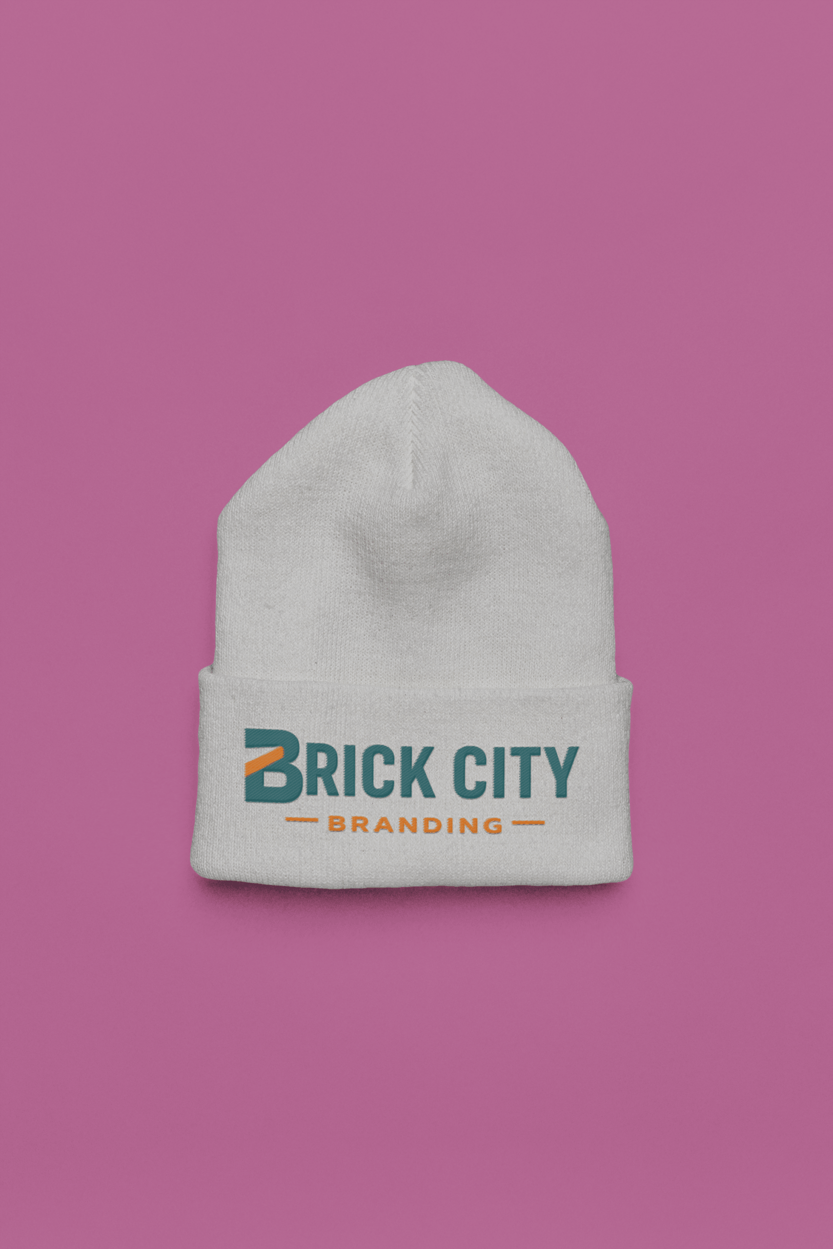 A white knit cuffed beanie featuring the Brick City Branding logo printed on the front cuff, centered against a solid purple background.