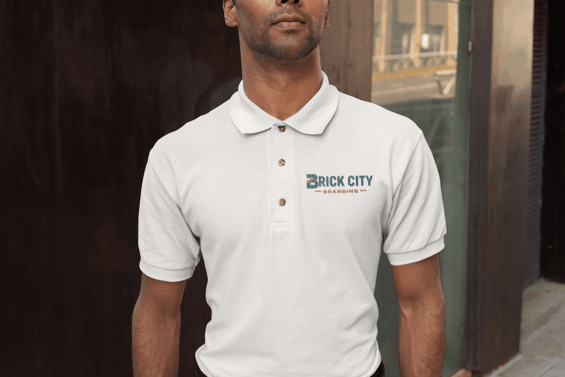 A man wearing a white custom polo shirt with the Brick City Branding logo embroidered on the left chest and custom equine gear, standing in an urban outdoor setting. Student Organization Screen Printing