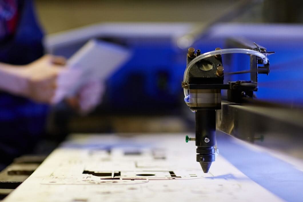 Laser engraving head working on material with an operator in the background