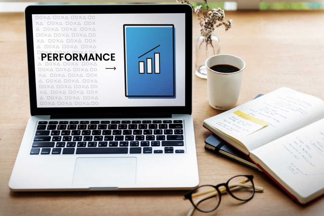 Laptop on an office desk displaying a performance growth chart with a notebook, glasses, and coffee cup in Newark, NJ.