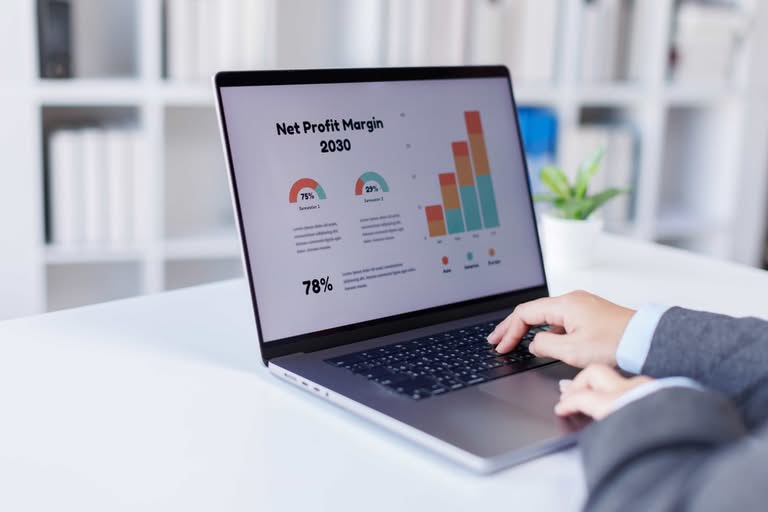 Close-up of a professional using a laptop to analyze a net profit margin dashboard with colorful growth charts, illustrating business financial strategy in Orlando, FL.